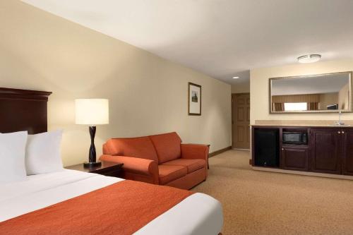 ポート・ウェントワースにあるCountry Inn & Suites by Radisson, Savannah I-95 Northのベッドと椅子付きのホテルルーム
