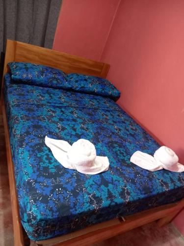 Una cama con dos sombreros y toallas. en Casa Astridainara, en Puerto Jiménez