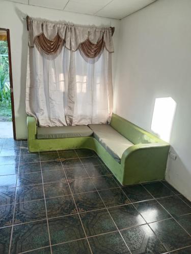 un sofá verde en una habitación con ventana en Casa Astridainara, en Puerto Jiménez