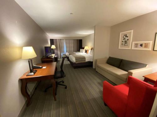 a hotel room with a desk and a couch and a bed at Country Inn & Suites by Radisson, Athens, GA in Athens