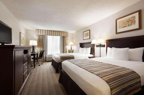 a hotel room with two beds and a flat screen tv at Country Inn & Suites by Radisson, Kingsland, GA in Kingsland
