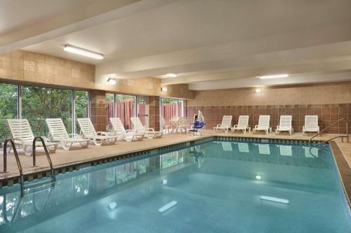 a swimming pool in a hotel with chairs and a person at Country Inn & Suites by Radisson, Newnan, GA in Newnan