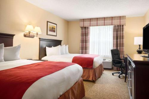 a hotel room with two beds and a television at Country Inn & Suites by Radisson, Norcross, GA in Norcross