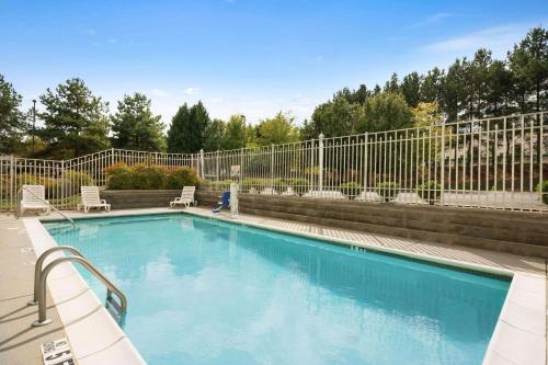 uma piscina com cadeiras e uma cerca em Country Inn & Suites by Radisson, Norcross, GA em Norcross