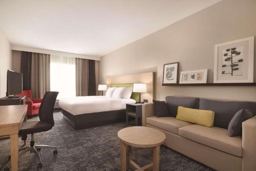 une chambre d'hôtel avec un lit et un canapé dans l'établissement Country Inn & Suites by Radisson, Macon West, GA, à Macon