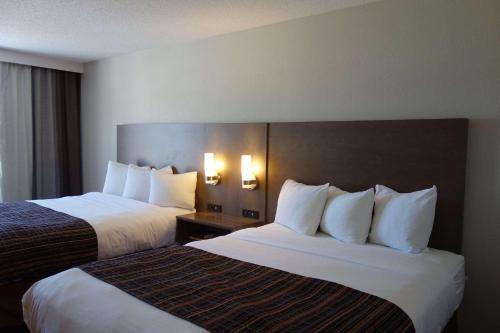 two beds in a hotel room with white pillows at Country Inn & Suites by Radisson, Mason City, IA in Mason City