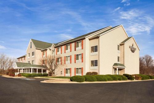 a large white building with red windows on a street at Country Inn & Suites by Radisson, Clinton, IA in Clinton