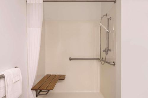 a bathroom with a shower with a wooden bench in it at Country Inn & Suites by Radisson, Cedar Falls, IA in Cedar Falls