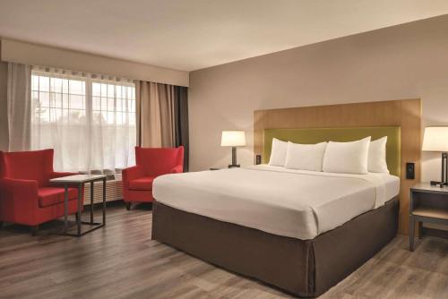 a hotel room with a large bed and red chairs at Country Inn & Suites by Radisson, Cedar Falls, IA in Cedar Falls