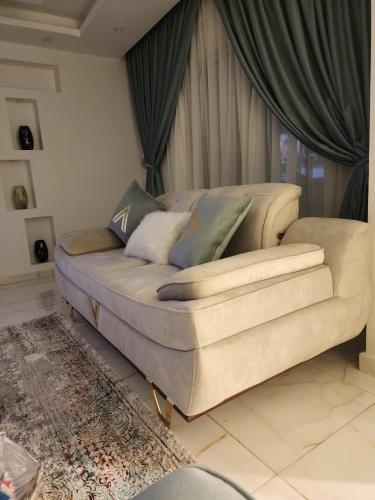 un sofá sentado en una sala de estar con cortinas en شقة فارهة, en El Cairo