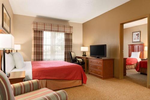 a hotel room with a bed and a television at Country Inn & Suites by Radisson, Sycamore, IL in Sycamore