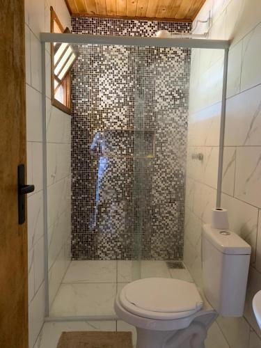 a bathroom with a toilet and a glass shower at CASA DO BOSQUE in Imbituba