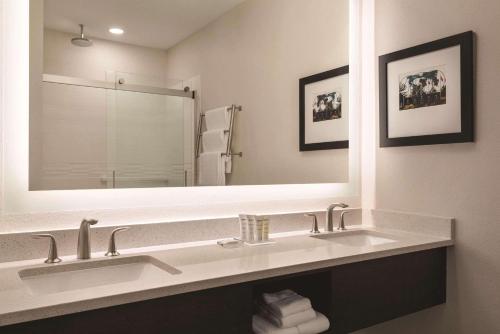 baño con 2 lavabos y espejo grande en Radisson Hotel & Conference Center Rockford, en Rockford