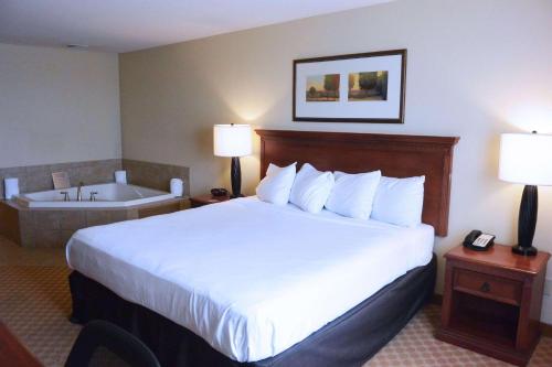 a hotel room with a bed and a bath tub at Country Inn & Suites by Radisson, Peoria North, IL in Peoria