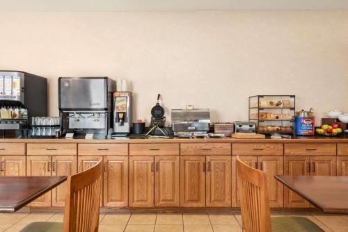 Una cocina con gabinetes de madera y mesas y sillas de madera. en Country Inn & Suites by Radisson, Peoria North, IL, en Peoria