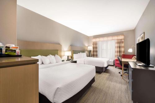 a hotel room with two beds and a television at Country Inn & Suites by Radisson, Freeport, IL in Freeport