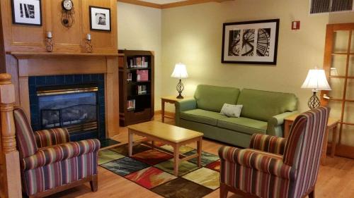 a living room with a green couch and a fireplace at Country Inn & Suites by Radisson, Bloomington-Normal West, IL in Bloomington