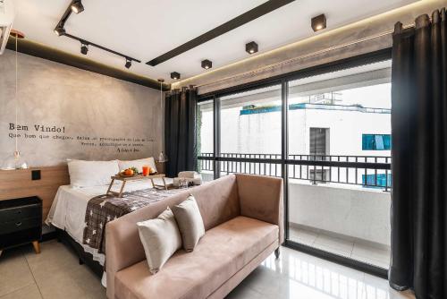 een slaapkamer met een bed en een bank bij MS906 Studio Encantador na Bela Vista in Sao Paulo