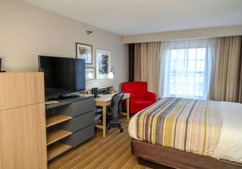 een hotelkamer met een bed en een bureau met een televisie bij Country Inn & Suites by Radisson, Greenfield, IN in Greenfield