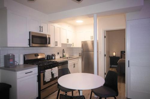 a kitchen with white cabinets and a white table with chairs at Ocean Way One Bedroom in Los Angeles