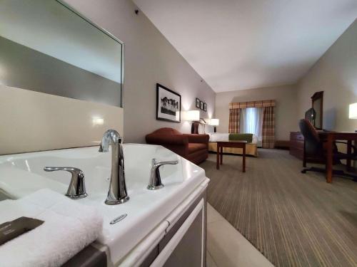 Country Inn & Suites by Radisson, Paducah, KY في بادوكا: حمام مع حوض وغرفة معيشة