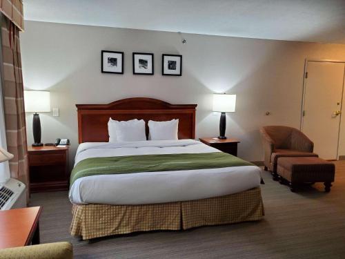 パデューカにあるCountry Inn & Suites by Radisson, Paducah, KYの大きなベッドと椅子が備わるホテルルームです。
