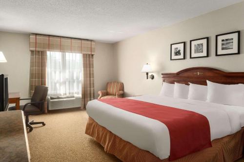 a hotel room with a large bed and a chair at Country Inn & Suites by Radisson, Louisville South, KY in Shepherdsville