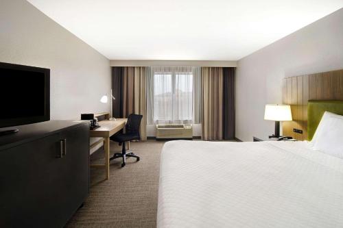 a hotel room with a bed and a desk with a computer at Country Inn & Suites by Radisson, Cincinnati Airport, KY in Hebron