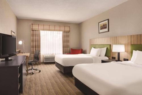 ジョージタウンにあるCountry Inn & Suites by Radisson, Georgetown, KYのベッド2台、薄型テレビが備わるホテルルームです。