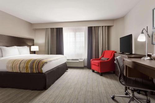 a hotel room with a bed and a desk and a red chair at Country Inn & Suites by Radisson, Shreveport-Airport, LA in Shreveport