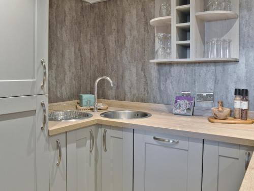 a kitchen with white cabinets and a sink at Elfin Cottage - Uk7810 in Coirantee