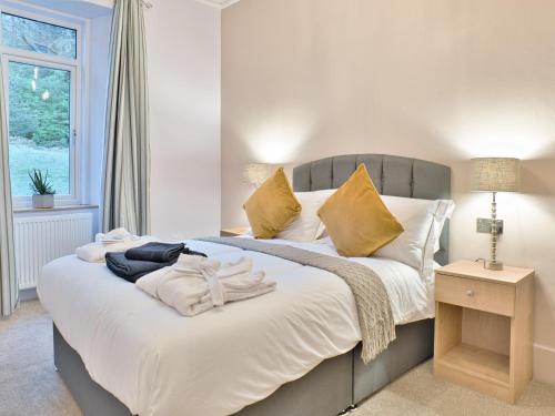 1 dormitorio con 1 cama con sábanas blancas y almohadas amarillas en Elfin Cottage - Uk7810 en Coirantee