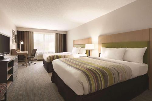 キャピトル・ハイツにあるCountry Inn & Suites by Radisson, Washington, D.C. East - Capitol Heights, MDのベッド2台とデスクが備わるホテルルームです。
