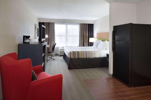 une chambre d'hôtel avec un lit et un fauteuil rouge dans l'établissement Country Inn & Suites by Radisson, Camp Springs Andrews Air Force Base , MD, à Camp Springs