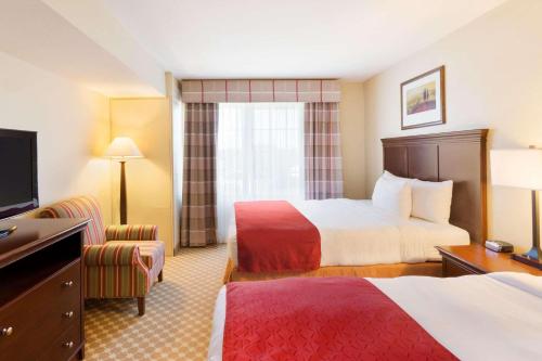 a hotel room with two beds and a television at Country Inn & Suites by Radisson, Covington, LA in Covington
