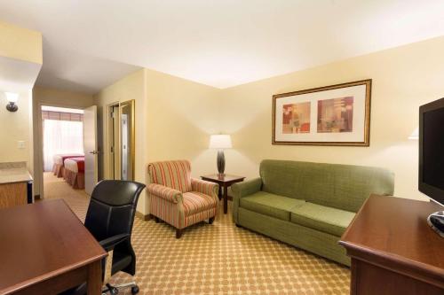 a living room with a green couch and a bed at Country Inn & Suites by Radisson, Covington, LA in Covington