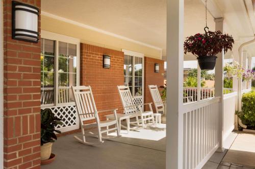 a porch with white rocking chairs on a house at Country Inn & Suites by Radisson, Covington, LA in Covington