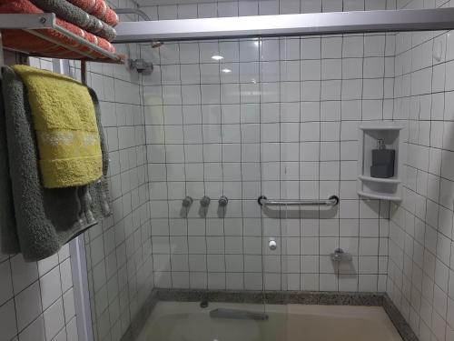 uma casa de banho em azulejos brancos com uma banheira e uma toalha amarela em Flat no Sol Vitória Marina 2 em Salvador