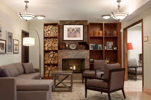 a living room with a fireplace and a couch and chairs at Country Inn & Suites by Radisson, Dearborn, MI in Dearborn