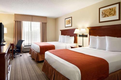 Cette chambre comprend deux lits et une télévision. dans l'établissement Country Inn & Suites by Radisson, Baltimore North, MD, à White Marsh