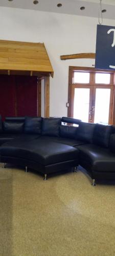 a black leather couch in a room with two windows at spacious former store 