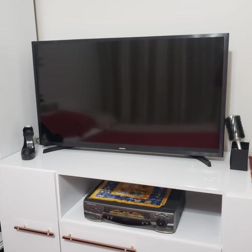 telewizor z płaskim ekranem siedzący na białej półce w obiekcie Gringo Habitación Casa 2 w mieście São Gabriel