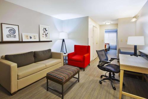 sala de estar con sofá y silla roja en Country Inn & Suites by Radisson, Big Rapids, MI, en Big Rapids