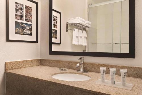 Country Inn & Suites by Radisson, Eagan, MN في ايجان: حمام مع حوض ومرآة