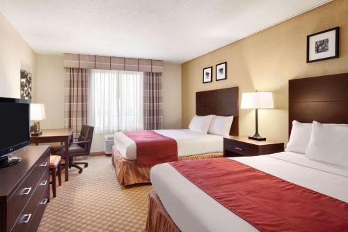 a hotel room with two beds and a desk at Country Inn & Suites by Radisson, Coon Rapids, MN in Coon Rapids