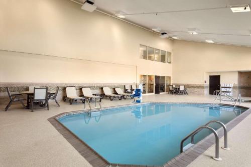 uma grande piscina com cadeiras e mesas em Country Inn & Suites by Radisson, Coon Rapids, MN em Coon Rapids