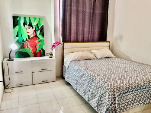 a bedroom with a bed and a painting on the wall at Habitación amoblada con servicios Rio mar in Barranquilla