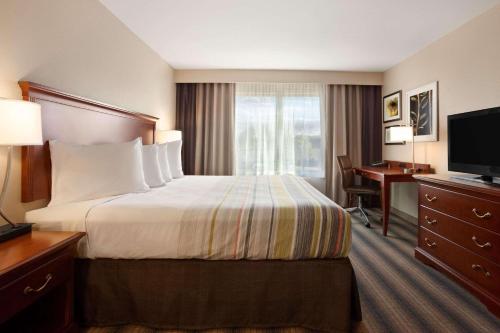 a hotel room with a bed and a desk and a television at Country Inn & Suites by Radisson, Roseville, MN in Roseville