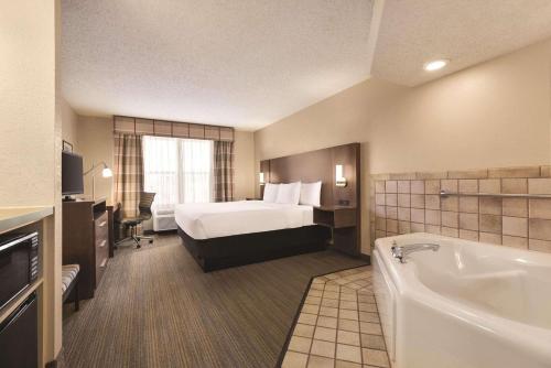 a hotel room with a bed and a bath tub at Country Inn & Suites by Radisson, Forest Lake, MN in Forest Lake