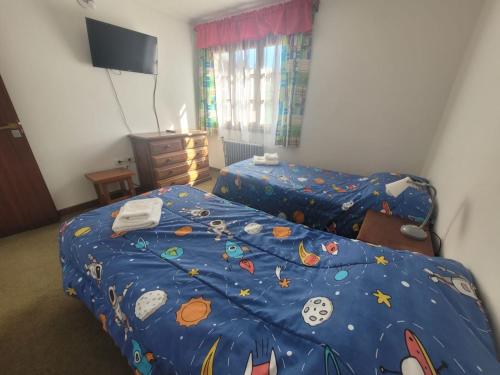 1 dormitorio con 2 camas y edredón azul en Los Maitenes en Dina Huapi